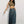 Vrouw in trendy outfit met olijfgroene crop top, lange denim rok en witte sneakers, poseert tegen witte achtergrond. Mode, casual stijl, streetwear.