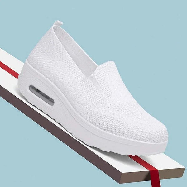 Witte dames sneaker met luchtkussen zool, ademend mesh bovenwerk, slip-on design, op blauwe achtergrond. Comfortabele en modieuze schoenen.