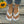 Vrouwelijke voeten met witte teenslippers en vlinderdecoratie, witte nagellak, enkelbandjes, op houten vloer met zonnebloem. Zomer modeaccessoires.