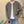 Man in beige gebreid vest met zakken, witte T-shirt en blauwe jeans, staand tegen een bakstenen muur. Casual herenkleding, moderne stijl.