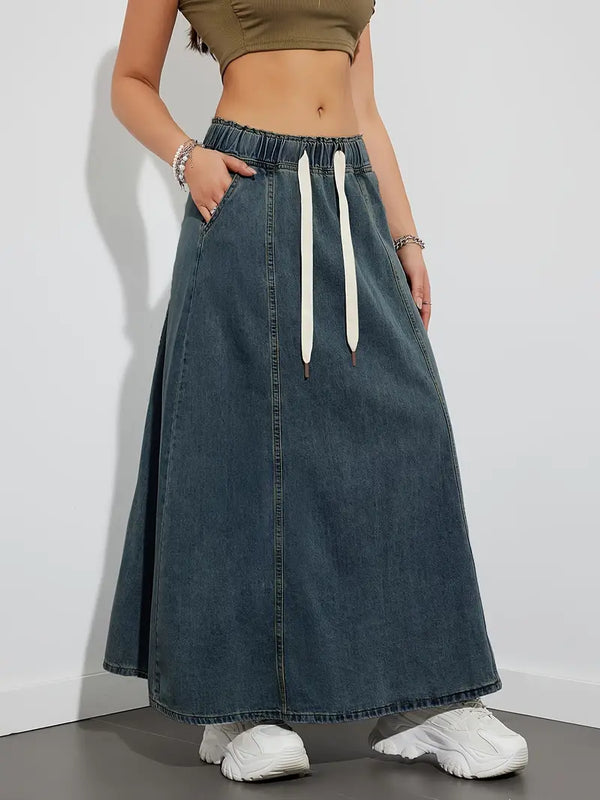 Vrouw in denim maxi-rok met elastische tailleband en witte sneakers, casual mode, trendy dameskleding, comfortabele streetwear-stijl.