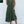 Groene zomerjurk met knopen, mouwloos en met ruches, gedragen door vrouw. Perfect voor casual zomeroutfits. Trendy damesmode 2023.