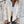 Vrouw in beige corduroy jack met capuchon, witte top en donkere jeans tegen een betonnen muur. Modieuze casual dameskleding, herfststijl.