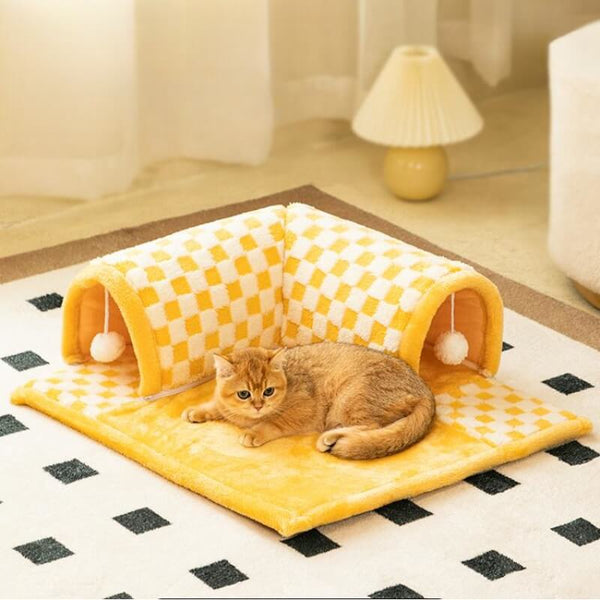 Pluche kattenbed en tunnel in één, geel-wit geruit ontwerp, met kat liggend op het zachte oppervlak. Ideaal voor kattencomfort en speelplezier.