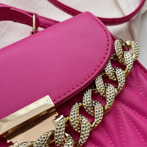 Roze handtas met gouden ketting en gesp, stijlvolle damesaccessoire, modieuze tas voor dagelijks gebruik, trendy design, luxe uitstraling.