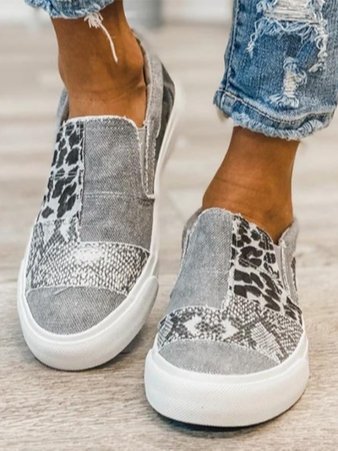Grijze canvas instappers met dierenprint, gedragen door persoon in gescheurde jeans. Trendy casual schoenen voor dames, comfortabel en stijlvol.