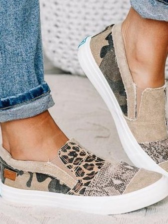 Trendy canvas instappers met camouflage- en luipaardprint, gedragen met opgerolde jeans. Comfortabele damesmode, casual schoenen.