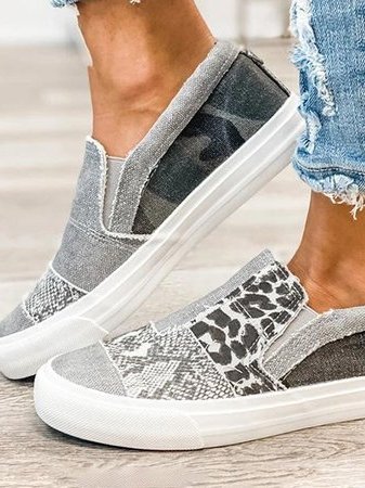 Grijze canvas instappers met dierenprint en witte zool, gedragen met gescheurde jeans. Trendy en casual schoenen voor dames.