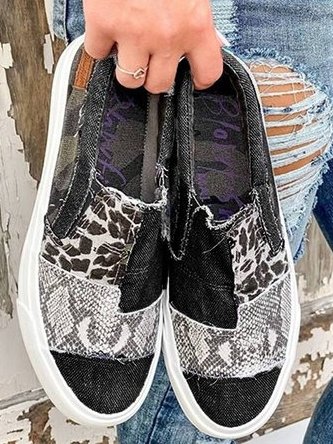 Zwarte canvas instappers met dierenprint en witte zool, trendy en casual. Perfect voor dagelijks gebruik. Comfortabele en modieuze damesschoenen.
