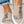 Trendy canvas instappers met dierenprint en patchwork design, gedragen door persoon in opgerolde jeans. Comfortabele en modieuze schoenen.