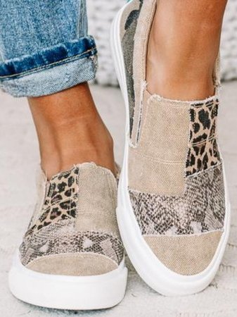 Trendy canvas instappers met dierenprint en patchwork design, gedragen door persoon in opgerolde jeans. Comfortabele en modieuze schoenen.