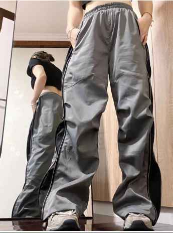Grijze en zwarte trainingsbroek met wijde pijpen, gedragen door een persoon in een spiegel. Sportieve mode, comfortabele pasvorm, casual stijl.