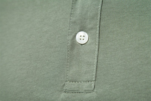 Groene polo met knoopsluiting, close-up van stof en witte knoop. Hoogwaardige herenkleding, casual stijl, comfortabele pasvorm.