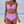 Vrouw in roze bikini met hoge taille, strandachtergrond. Modieuze badmode, zomerstijl, strandkleding, dames zwemkleding.