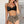 Vrouw in zwarte bikini-top en luipaardprint hoge taille bikini-slip tegen witte bakstenen muur. Zomermode, strandkleding, trendy badmode.