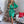 Vrouw in groene satijnen jurk voor versierde kerstboom, omringd door cadeaus. Kerstdecoratie, feestelijke mode, elegante avondjurk.