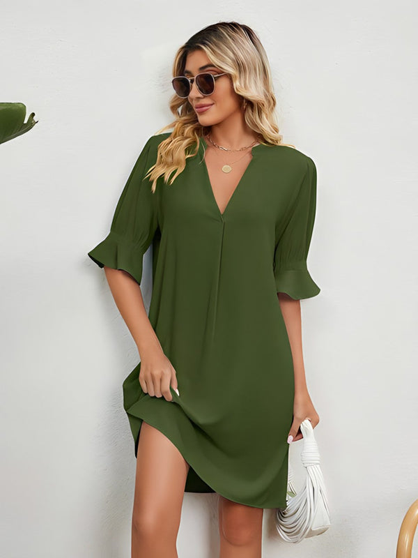Vrouw in groene zomerjurk met driekwart mouwen, draagt zonnebril en witte handtas. Modieuze dameskleding, casual stijl, trendy outfit.