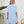 Vrouw in lichtblauwe jurk met korte mouwen, staand in moderne kamer met plant en houten stoel. Elegante damesmode, zomerjurk, casual stijl.