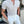Man in gestreept overhemd en witte broek leunt tegen muur. Modieuze herenkleding, zomerse outfit, casual stijl, trendy look.