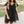 Vrouw in zwarte zomerjurk met stippenpatroon, korte mouwen en V-hals, wandelend in park. Trendy damesmode, casual outfit, buitenkleding.