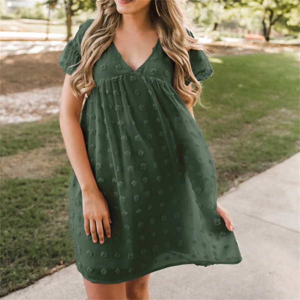Groene zomerjurk met bloemenpatroon, korte mouwen en V-hals, gedragen door vrouw in park. Perfect voor casual lente- en zomermode.