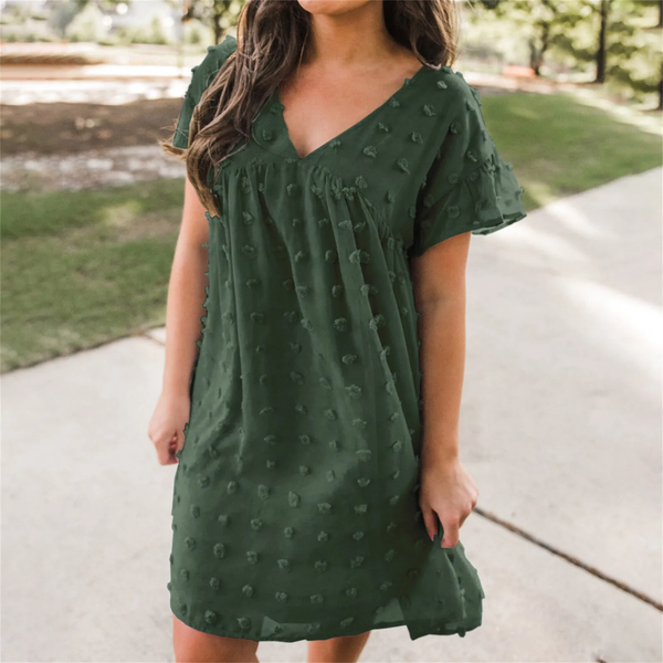 Groene zomerjurk met V-hals en korte mouwen, versierd met stippenpatroon. Perfect voor casual lente- en zomermode. Comfortabel en stijlvol.