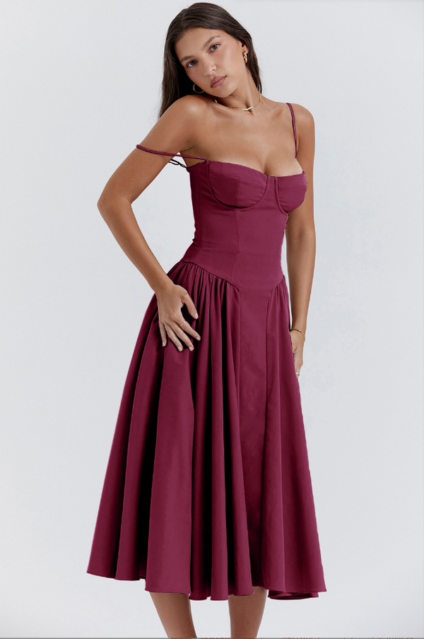 Vrouw in elegante bordeauxrode jurk met spaghettibandjes en geplooide rok, perfect voor avondkleding. Modieuze damesmode, stijlvolle jurk.