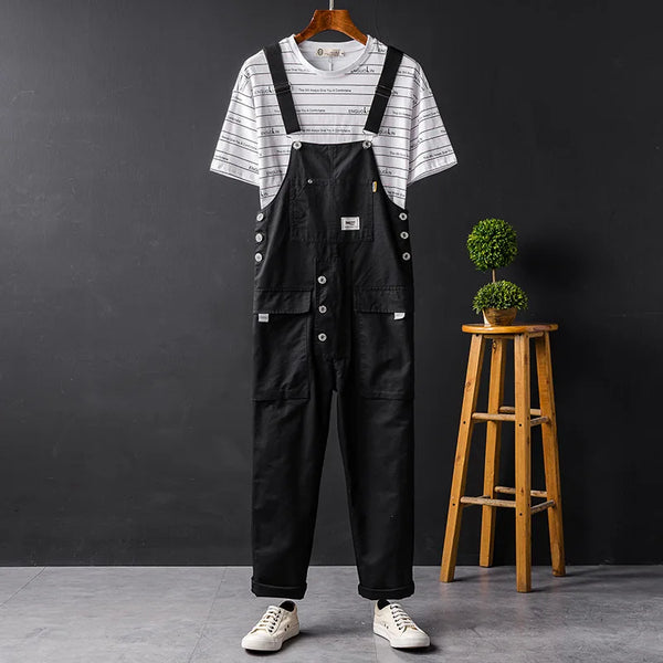 Zwarte cargobroek tuinbroek voor heren, hangend aan een hanger, met een gestreept T-shirt en witte sneakers. Stijlvolle zomeroutfit voor mannen.