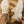 Beige sneakers met golvende witte zool, gedragen door persoon met gouden armband. Modieuze dames sneakers, casual stijl, comfortabele pasvorm.