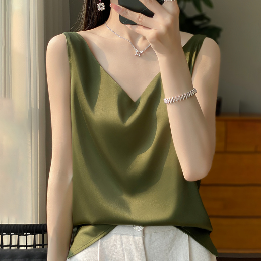 Vrouw in groene satijnen top, zonder mouwen, met V-hals, draagt zilveren sieraden. Stijlvolle zomermode, elegante dameskleding.