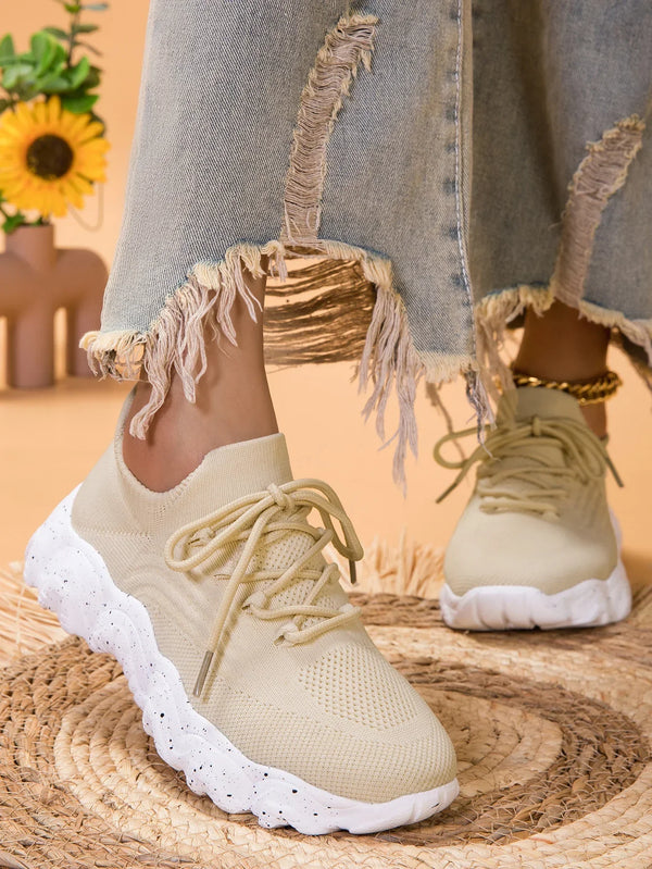 Beige sneakers met dikke witte zool, gedragen door persoon in gerafelde jeans. Modieuze casual schoenen, comfortabele pasvorm, trendy design.