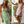 Twee vrouwen in zomerjurken met bloemenprint; links groene jurk, rechts roze jurk. Mode, zomerkleding, casual stijl, buitenomgeving.