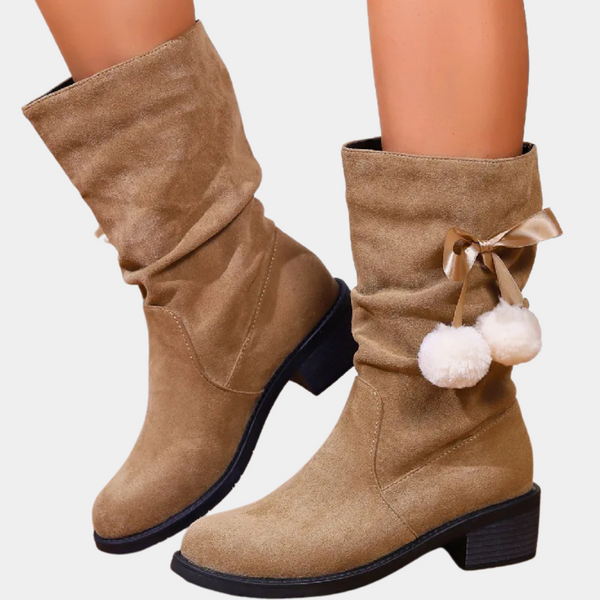 Beige suède laarzen met lage hak, pompons en strikdetail. Trendy damesmode, comfortabele winterlaarzen, stijlvol en veelzijdig voor dagelijks gebruik.