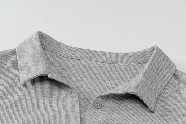 Grijze polo met kraag en knoopsluiting, gemaakt van geribbelde stof. Ideaal voor casual en zakelijke outfits. Comfortabel en stijlvol design.