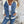 Vrouw in casual outfit met spijkerjasje en blauwe jeans tegen betonnen muur. Modieuze dameskleding, denim stijl, herfstmode.