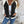 Vrouw in casual outfit met witte trui en zwarte spijkerjasje, blauwe jeans. Stijlvolle herfstmode, trendy dameskleding, stedelijke achtergrond.
