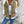 Vrouw in casual outfit met witte top, spijkerjas en blauwe jeans tegen een verweerde muur. Modieuze dameskleding, streetwear stijl.