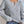 Grijze gebreide damestrui met V-hals, gedragen met blauwe jeans. Modieuze casual outfit, ideaal voor herfst- en winterseizoenen.