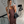 Vrouw in bruine geribbelde jurk maakt selfie in moderne interieur, met zwarte handtas en hoge laarzen. Stijlvolle mode, trendy outfit, elegante look.