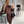 Vrouw in bruine geribbelde jurk maakt selfie, draagt zwarte tas en laarzen, moderne interieurachtergrond. Mode, herfstkleding, stijlvolle outfit.