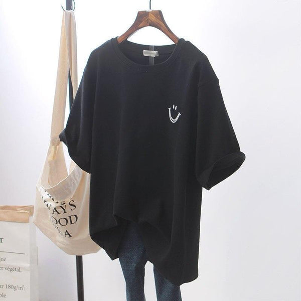 Zwarte dames T-shirt met lachend gezichtje, casual stijl, korte mouwen, katoenen stof, opgehangen aan houten hanger, naast canvas tas.