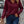 Vrouw in bordeauxrode geribbelde trui met halve rits, casual stijl, gecombineerd met blauwe jeans, modieuze herfstoutfit, stedelijke achtergrond.