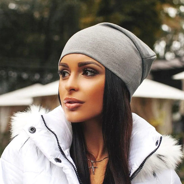 Vrouw met grijze beanie en witte winterjas met bontkraag, buiten in een herfstlandschap. Stijlvolle wintermode, trendy accessoires, herfstkleding.