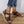 Bruine leren sandalen voor dames met klittenbandsluiting, gedragen met gescheurde jeans. Comfortabele zomerschoenen op houten vloer.