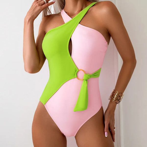 Vrouw in trendy roze-groene asymmetrische badpak met ringdetail, perfect voor zomer en strandmode. Stijlvolle damesbadmode, opvallend design.