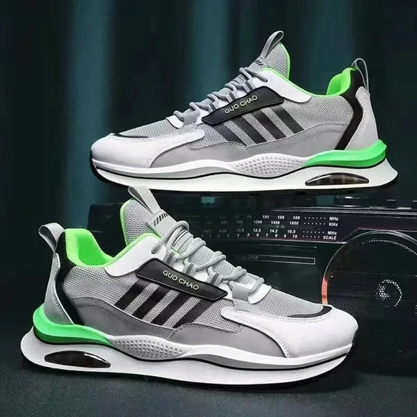 Grijze en groene sportschoenen met zwarte strepen en merknaam "QUO CHAO", gestyled op een donkere achtergrond. Moderne sneakers voor heren.