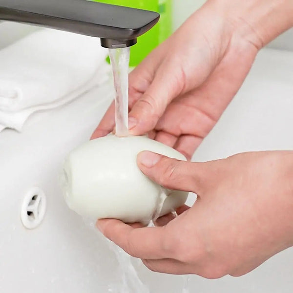 Handen wassen een witte zeep onder stromend water in een wastafel. Hygiëne, handreiniging, badkameraccessoires, dagelijkse verzorging.