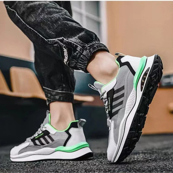 Grijze en witte sportschoenen met groene accenten, gedragen door een persoon in zwarte jeans. Moderne sneakers, comfortabele hardloopschoenen.