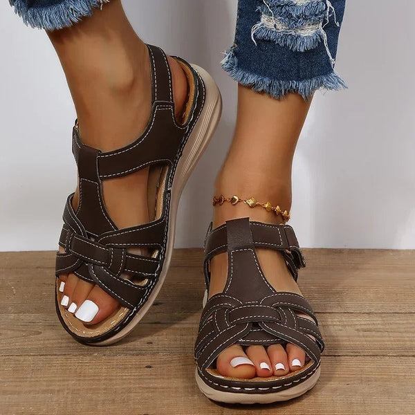 Bruine sandalen met open teen en verstelbare bandjes, gedragen door een persoon met een enkelbandje. Perfect voor zomerse casual outfits.