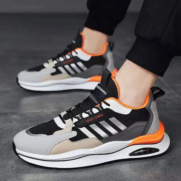 Zwart-grijze sportschoenen met oranje accenten, ademend mesh, en dempende zool. Ideaal voor hardlopen en casual gebruik. Unisex sneakers.